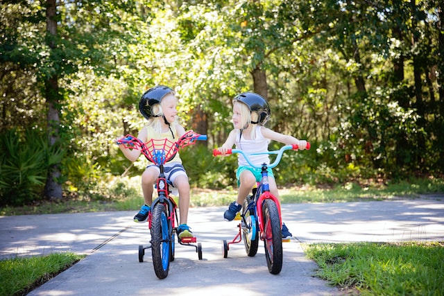 Two Girls riding bikes with training wheels