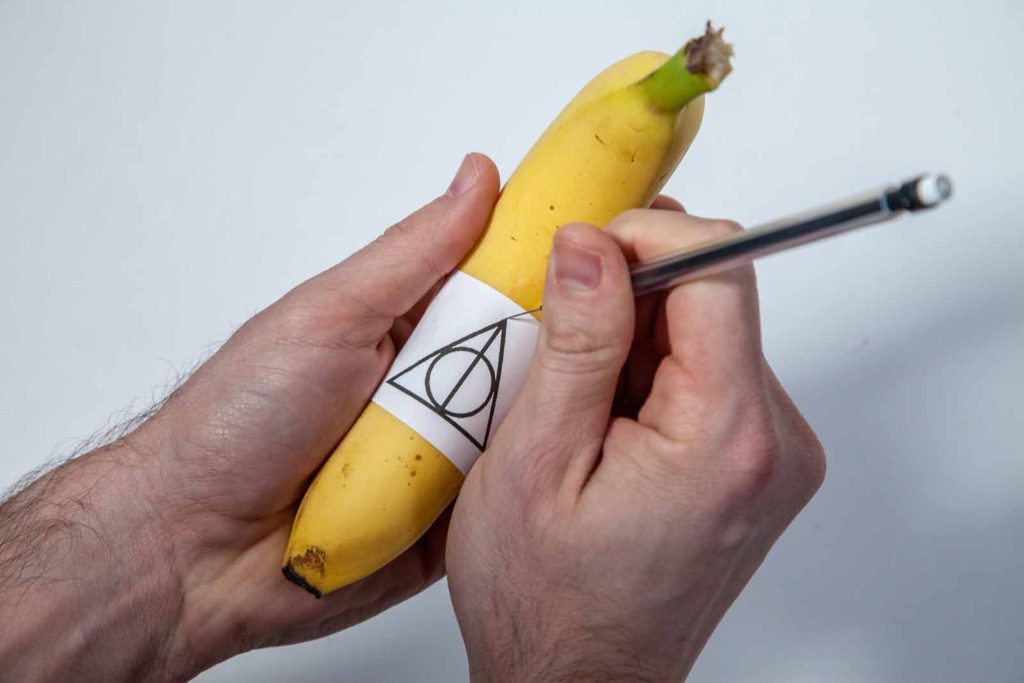 poking holes through a template to tattoo a banana